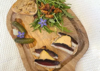 Planche de toasts magret de canard séché et foie gras, rillettes de canard et grillons de canard. Planche agrémentée de fleurs bourrache comestible, cornichons et roquette.