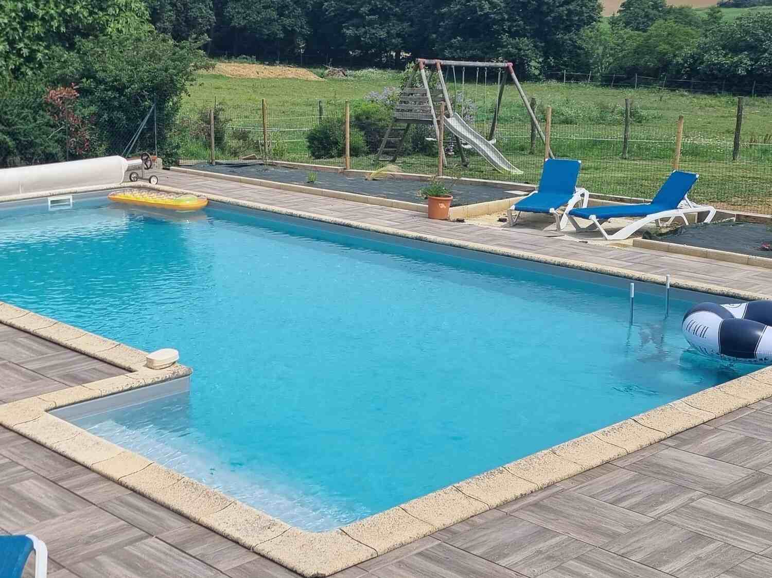 Piscine de la Ferme avec transats et vue du jardin avec balançoire